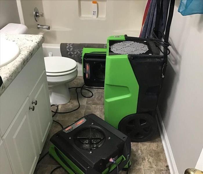 3 pieces of green SERVPRO drying equipment in a residential bathroom that experienced a water loss