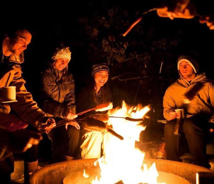 Group of friends by bonfire at night time