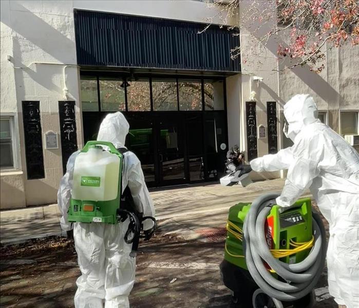 Two SERVPRO crew members in PPE headed to enter a large commercial building