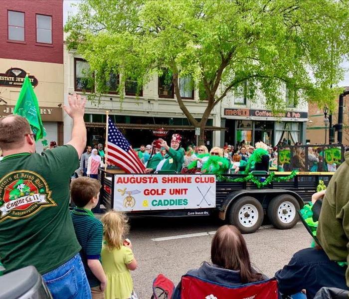 Augusta Shrine Club float waves to parade onlookers during a St. Patrick's Day celebration.