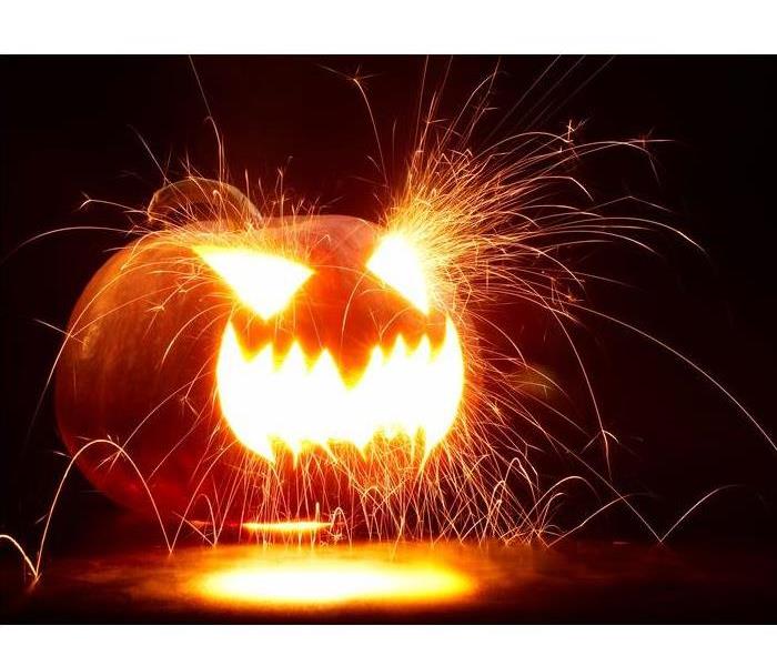 dark space with a orange pumpkin lit with sparks flying from its mouth and eyes